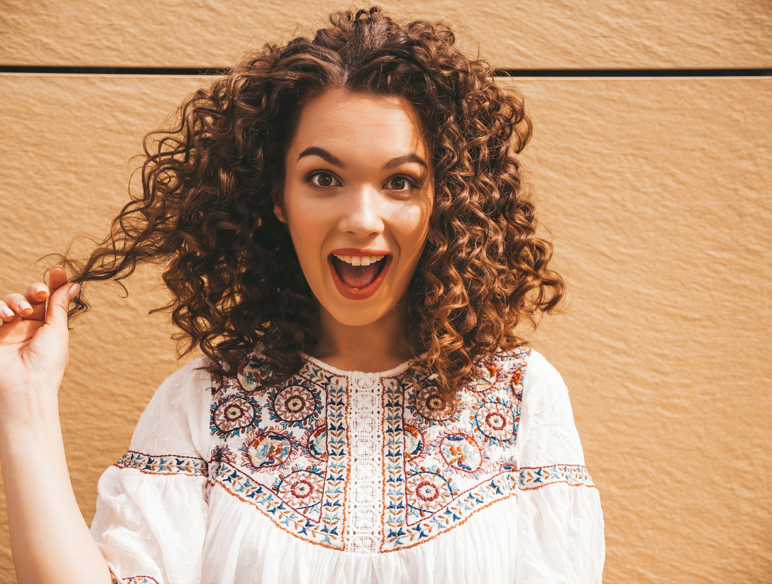 Femme avec de beaux cheveux bouclés bien entretenue à l'huile d'argan