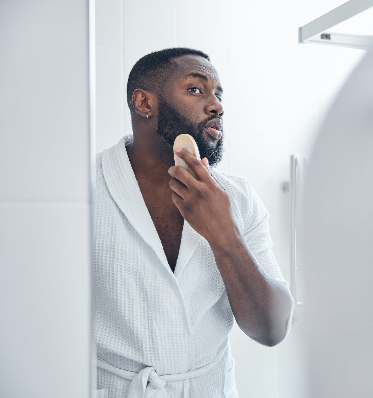 Homme élégant en peignoir qui se brosse la barbe.