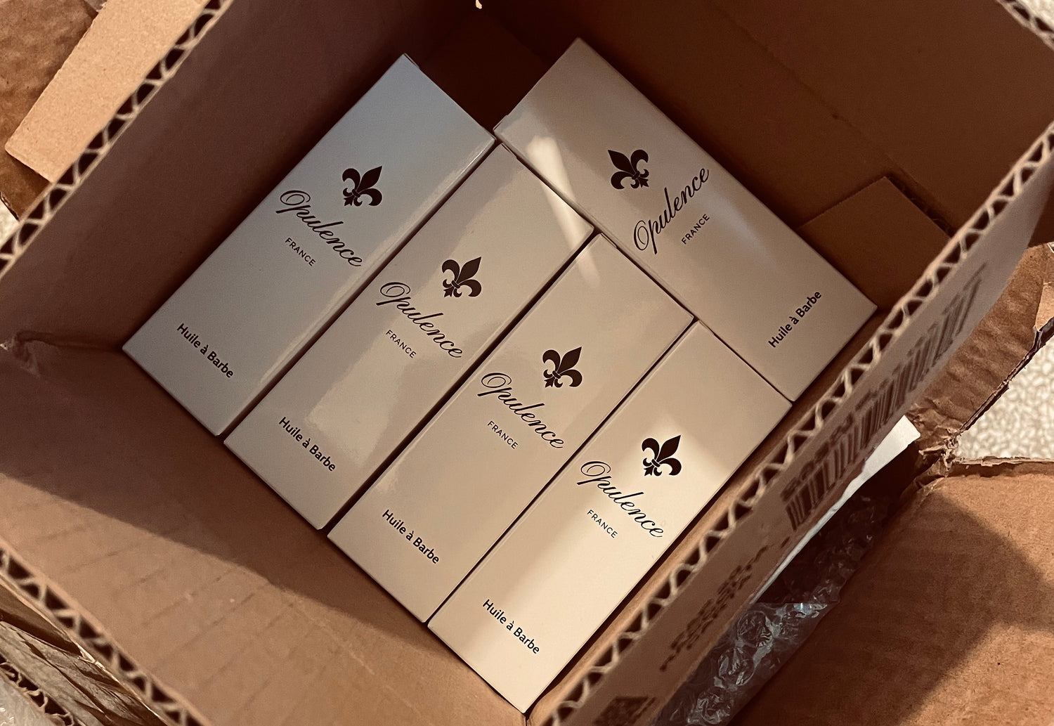 Huiles à barbes Opulence dans leur packaging entreposées dans un gros carton de couleur marron. 